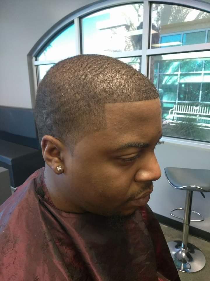 Man with waves and a clean fade line-up sitting in a barber chair