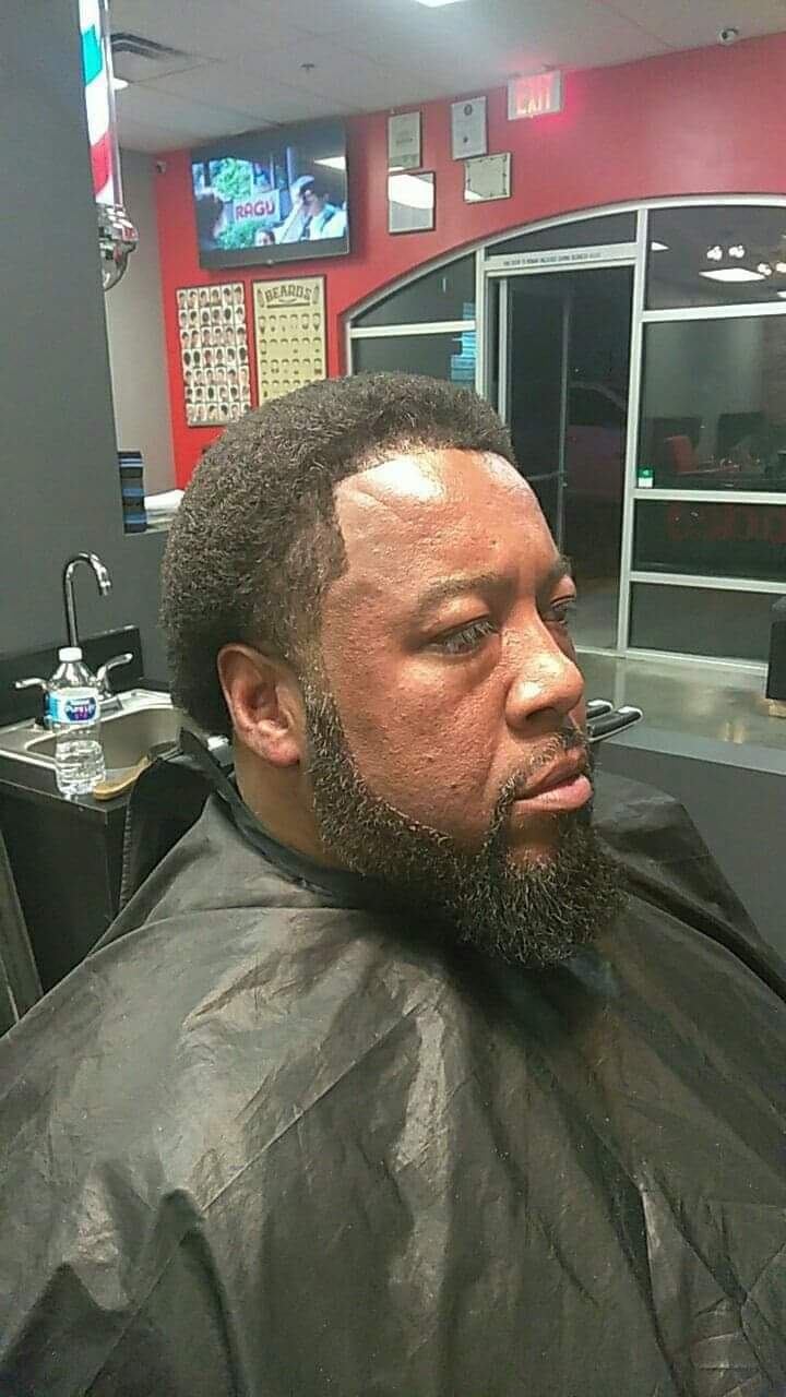 Man with a sharp beard line-up and haircut in a barber chair